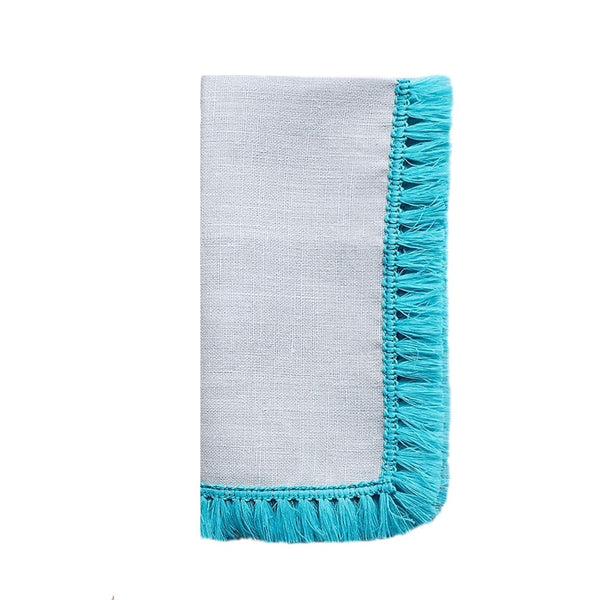 Folded Santorini napkin by Kim Seybert showcasing its texture and vibrant tuquoise fringe edge.