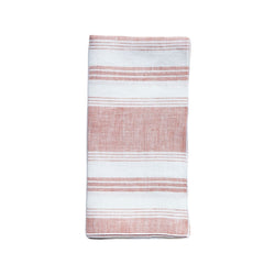Linen napkin with coral and white irregular stripes by Giardino Segreto on white background.