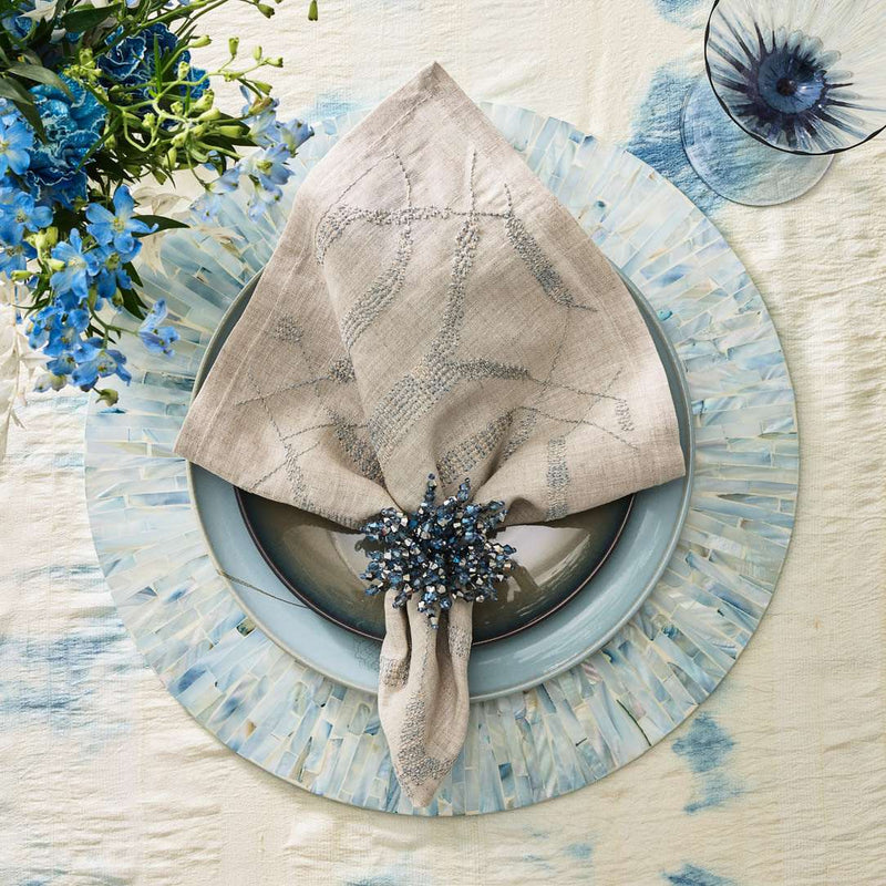 Styled variegated linen napkin on blue capiz shell placemat, top view, sold at Amiramour