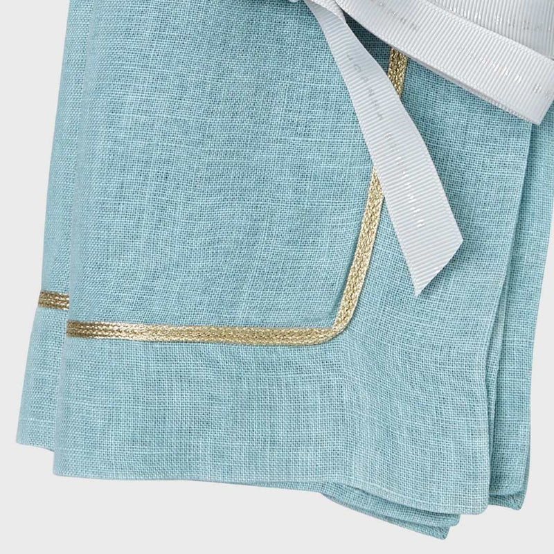 Close-up of gold trim on soft blue linen napkin by Joanna Buchanan, sold at Amiramour.