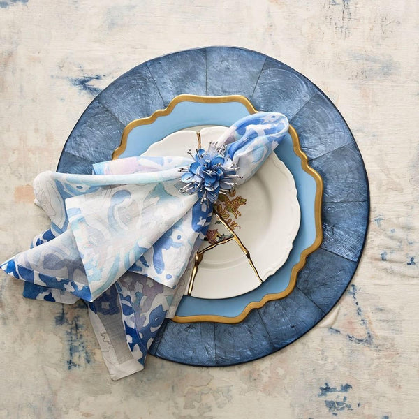Styled watercolour napkin by Kim Seybert on blue capiz shell placemat, sold at Amiramour.