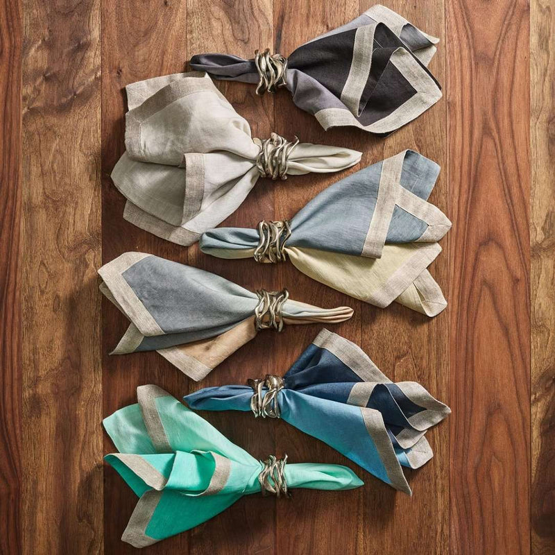 Grey and black ombre napkin with metallic foil border beside dip dye napkins in assorted colors.