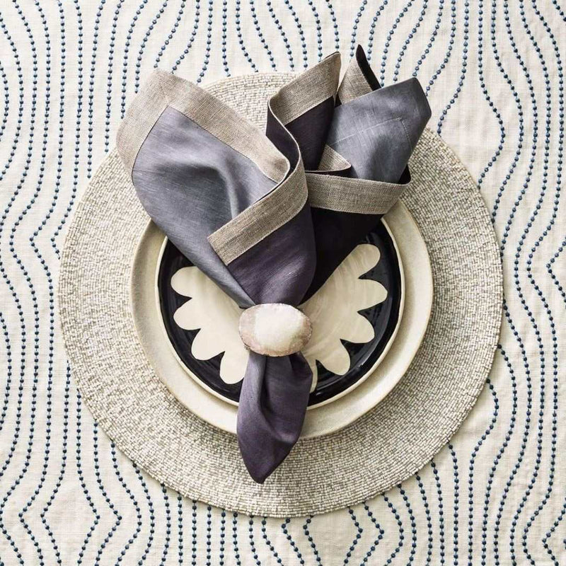 Grey and black ombre napkin with metallic foil border styled on beaded placemat.