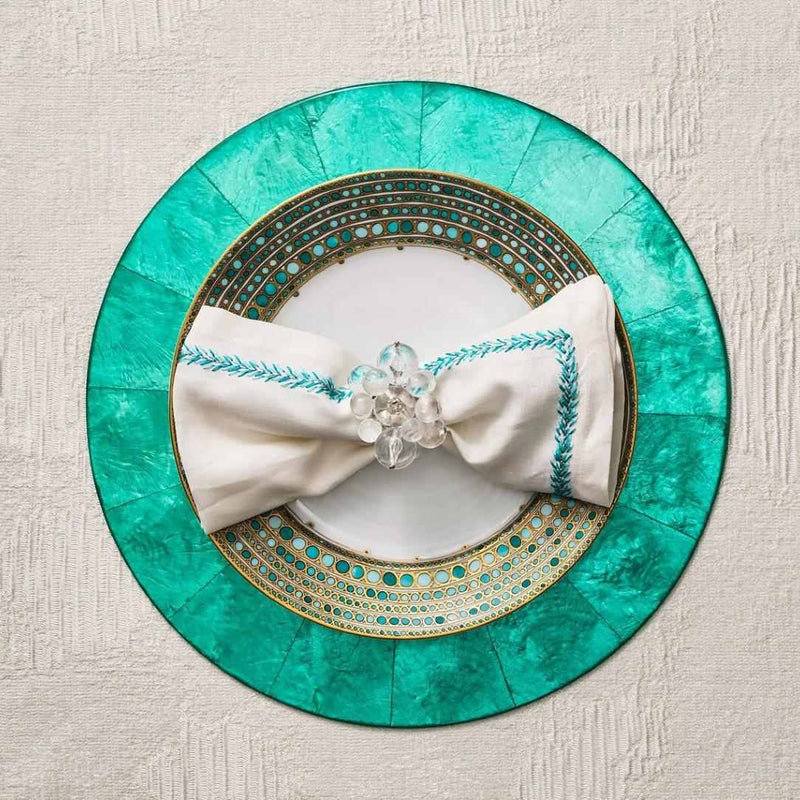 Top view of Jardin napkin on turquoise placemat in a refined table setting, presented by Amiramour