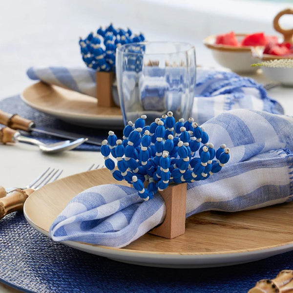 Close-up of summer table setting with beige and blue tones and Reed Napkin Rings