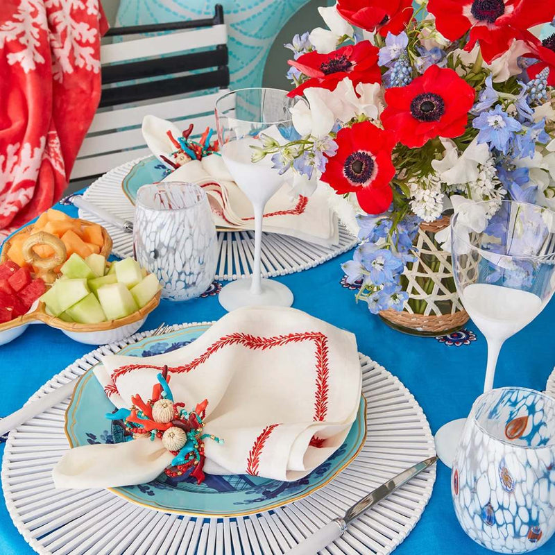 Close-up of summer table set with Coral Spray Napkin Rings by Kim Seybert from a side angle
