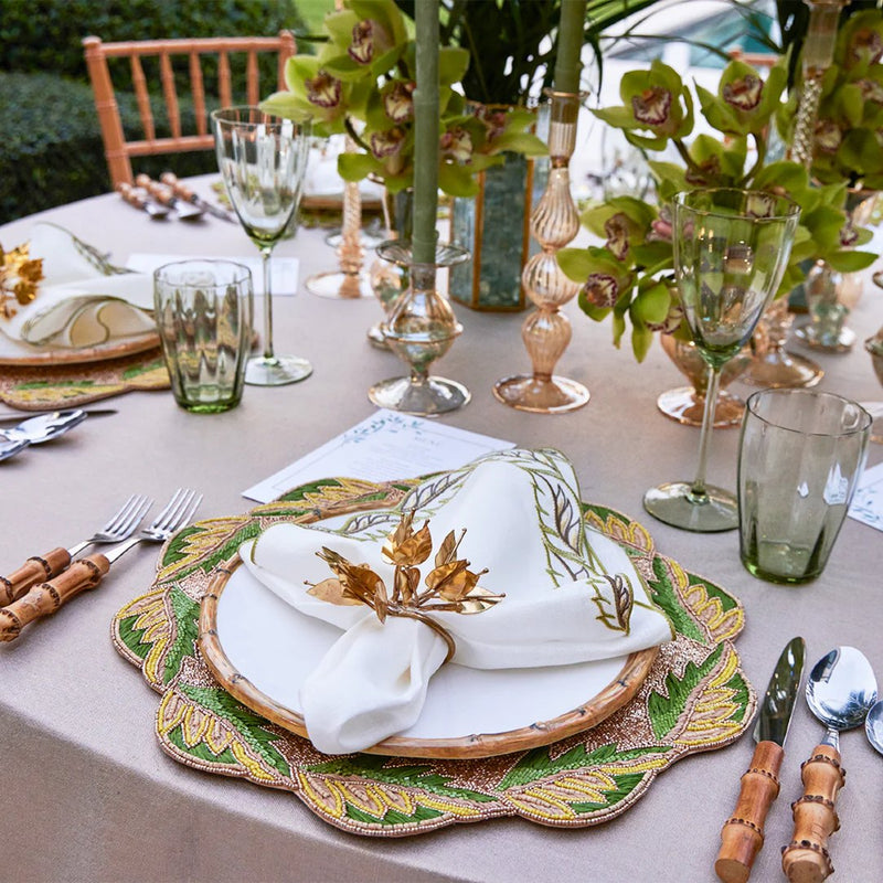 Close-up of green table setting with Bougainvillea Napkin Ring by Kim Seybert