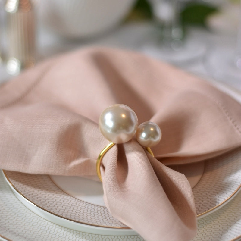 Detailed view of soft pink table decor featuring gold and ivory pearl napkin ring, available at Amiramour