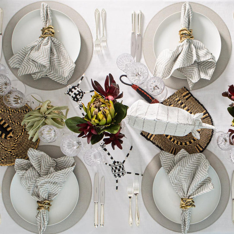 Top view of Afro-inspired table with light tones and Flux Napkin Ring by Kim Seybert as a gold accent