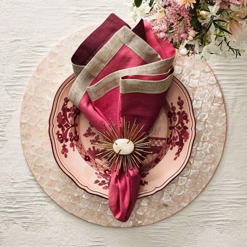 Blush pink Capiz shell placemat with red napkin.