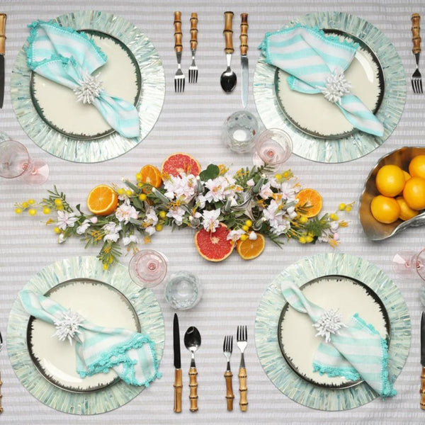 Round mother-of-pearl placemat in periwinkle blue by Kim Seybert on coastal tablescape.