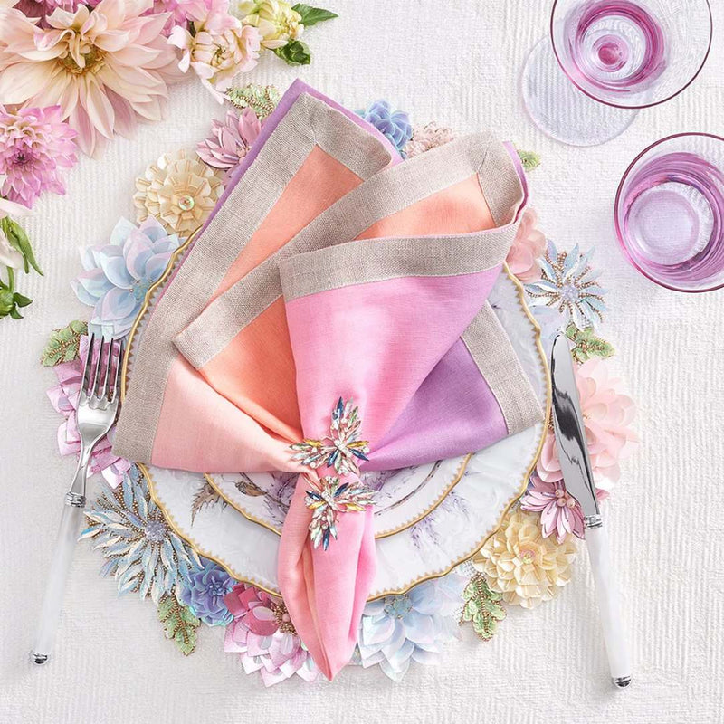 Hand-beaded Dahlia placemat in pastel pink, blue, and yellow styled with orange napkin.