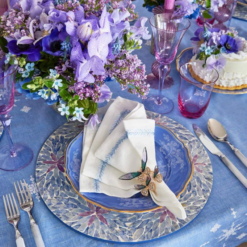 Lilac and periwinkle Capiz shell placemat with ombre floral design on blue floral tablescape.
