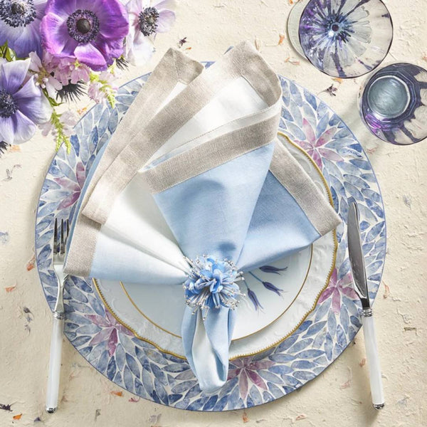 Lilac and periwinkle Capiz shell placemat with ombre floral design by Kim Seybert with blue napkin.