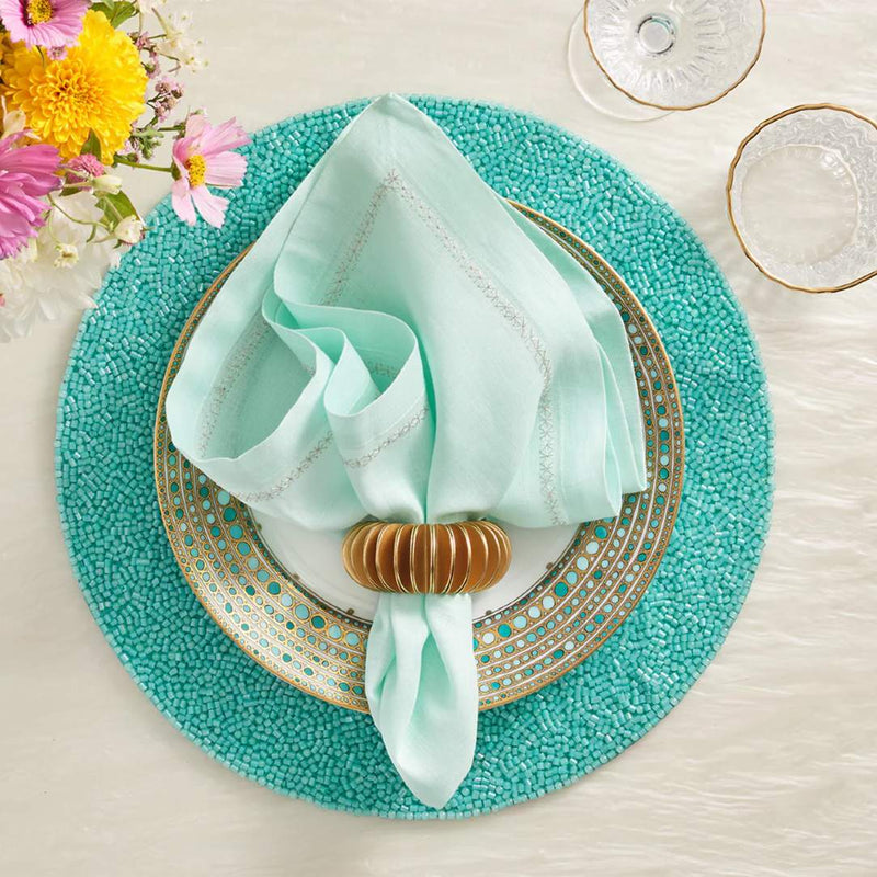 Turquoise placemat with translucent vermicelli beading with blue napkin.