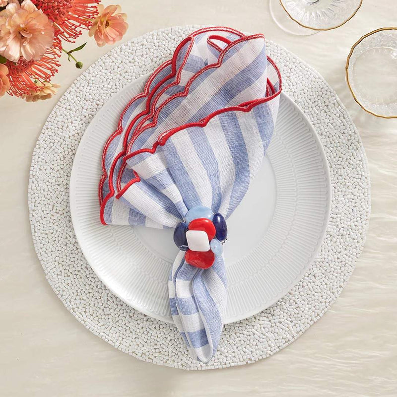 White beaded Perennial placemat with vermicelli pattern by Kim Seybert styled with blue striped napkin.