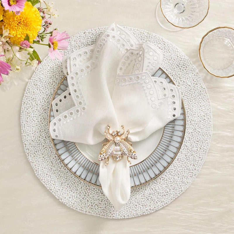 White beaded Perennial placemat with vermicelli pattern by Kim Seybert styled with bee napkin ring.