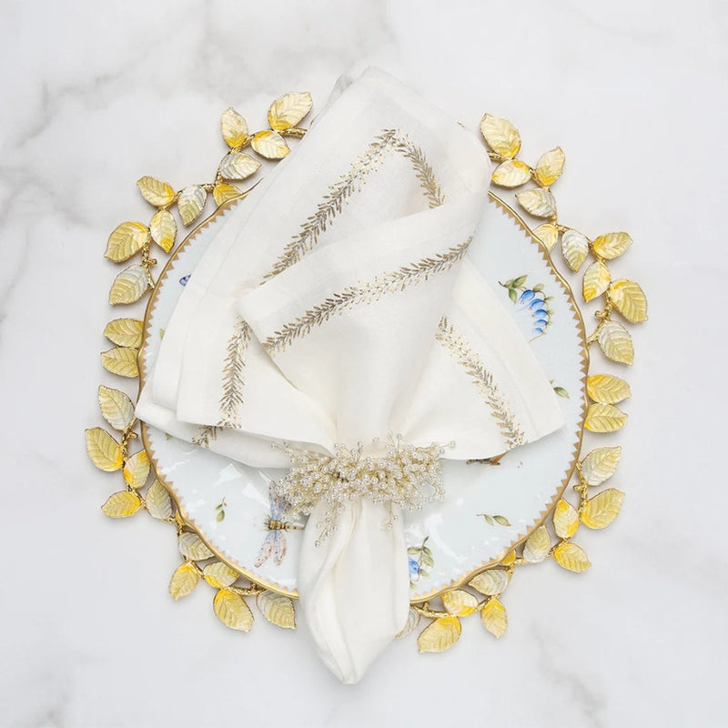 Gold and silver enamel charger with leaf motif by Kim Seybert ith white napkin.