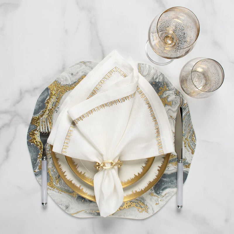 Kim Seybert Cosmos placemat with ivory, gold, and silver marbled design styled with gold napkin ring.