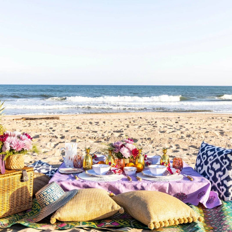 White spoke bamboo placemat by Kim Seybert styled on a beach table.