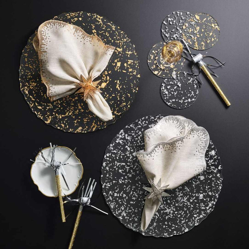 Clear acrylic placemat with silver flecks and wavy edge by Kim Seybert next to gold version.