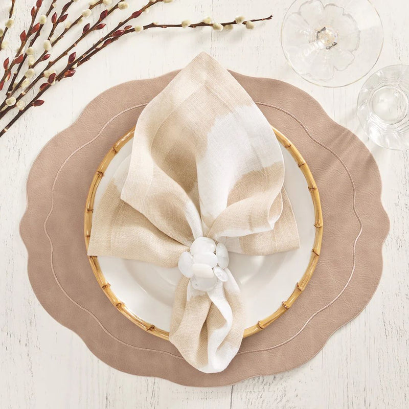 Kim Seybert taupe faux leather oval placemat with wavy edge with white napkin.