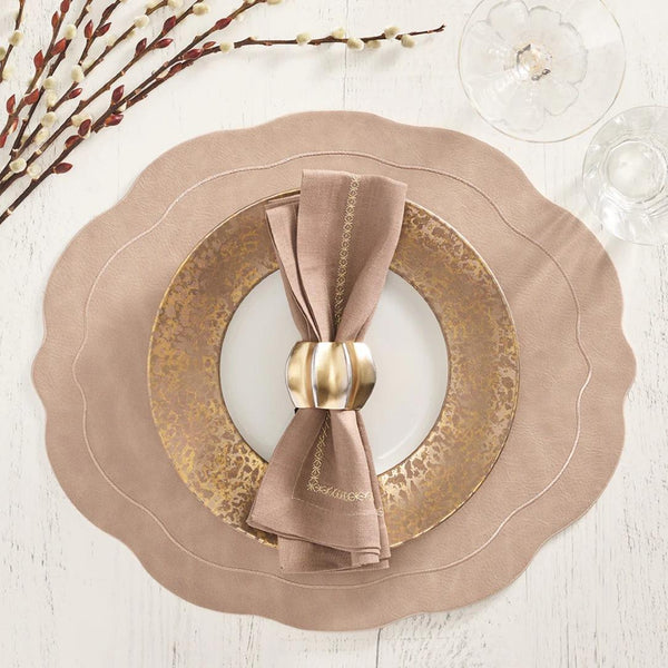 Kim Seybert taupe faux leather oval placemat with wavy edge styled with gold napkin ring.