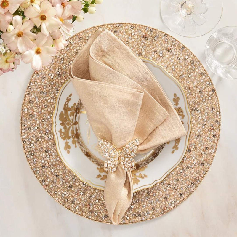 Hand-beaded champagne and crystal round placemat by Kim Seybert with gold napkin.