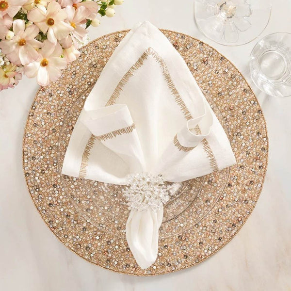 Hand-beaded champagne and crystal round placemat by Kim Seybert with white napkin.