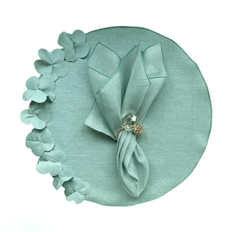 Sage green round linen placemat with 3D applied flowers with gold napkin ring.