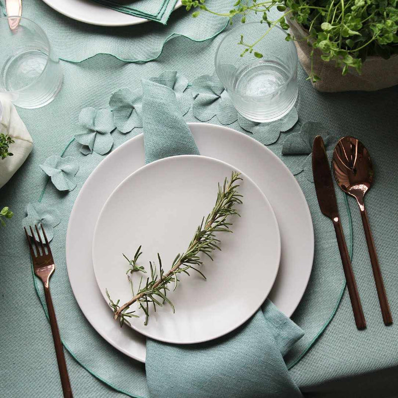 Sage green round linen placemat with 3D applied flowers with matching tableware.