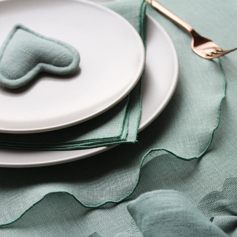 Garza round sage green linen placemat with drawstring hem close-up on hemstring.