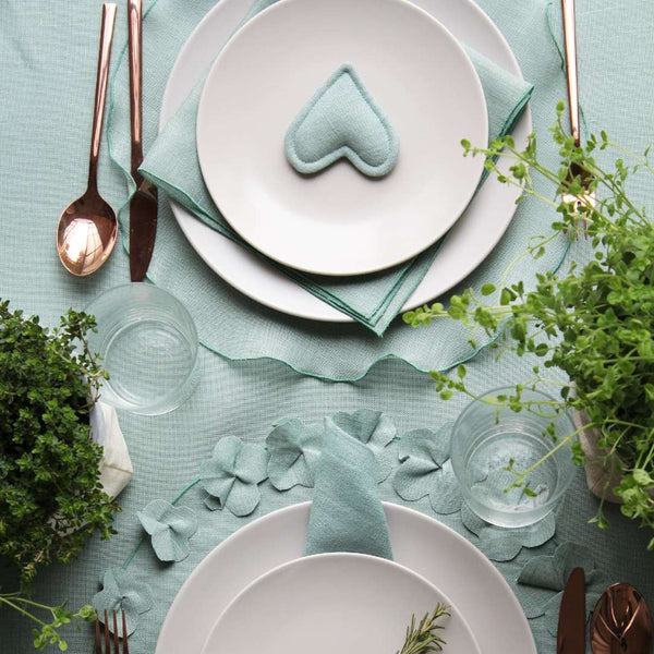 Garza round sage green linen placemat with drawstring hem with matching tableware.