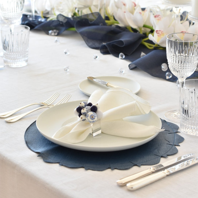 Blue coated linen placemat with fish design by Giardino Segreto on meiteranean tablescape.