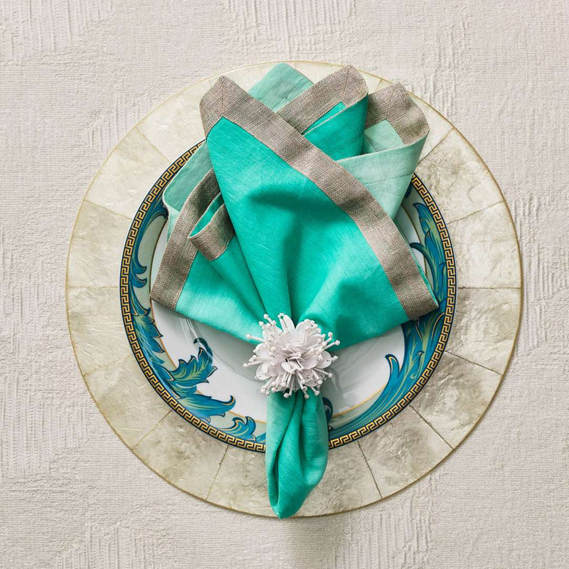 Natural Capiz shell round placemat with pearlescent finish by Kim Seybert with green napkin.