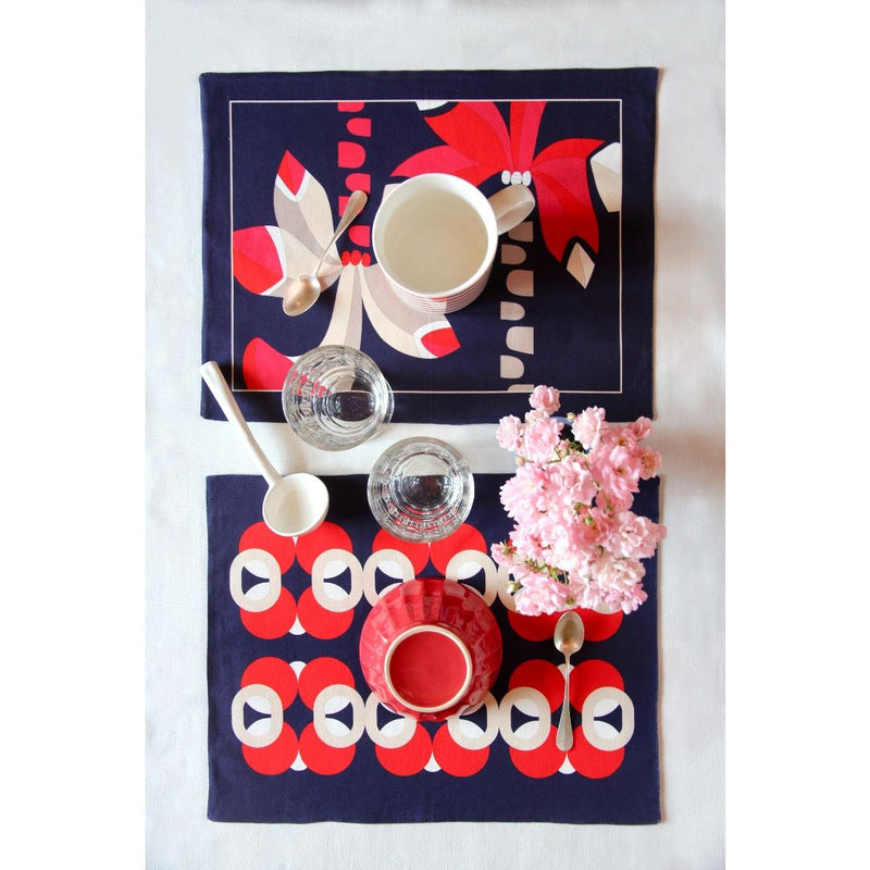 Reversible placemat with palm tree motif and vase design on breakfast table.