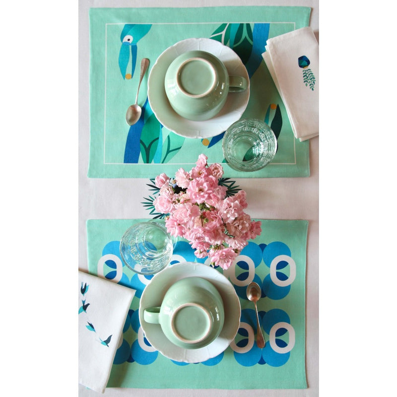 Reversible placemat with foliage motif and toucan design styled breakfast table.