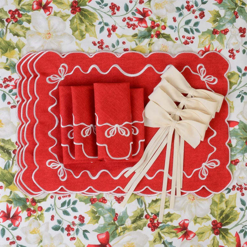 Red cotton placemat embroidered with white Christmas bows with matching bows and napkins.