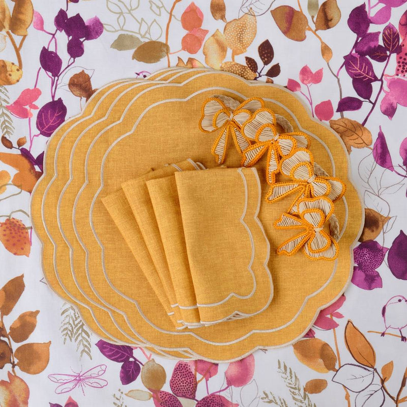 Yellow Petali Embroidered Placemats with wave border next to bows and napkins.