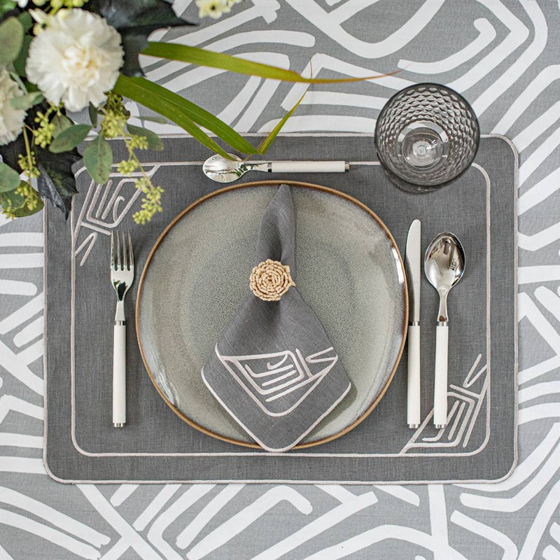 Gray linen placemat embroidered with minalist motif styled with trattan napkin rings.