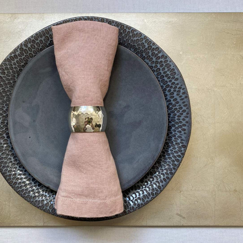 Champagne silver leaf placemat with matte lacquered finish with pink napkin.