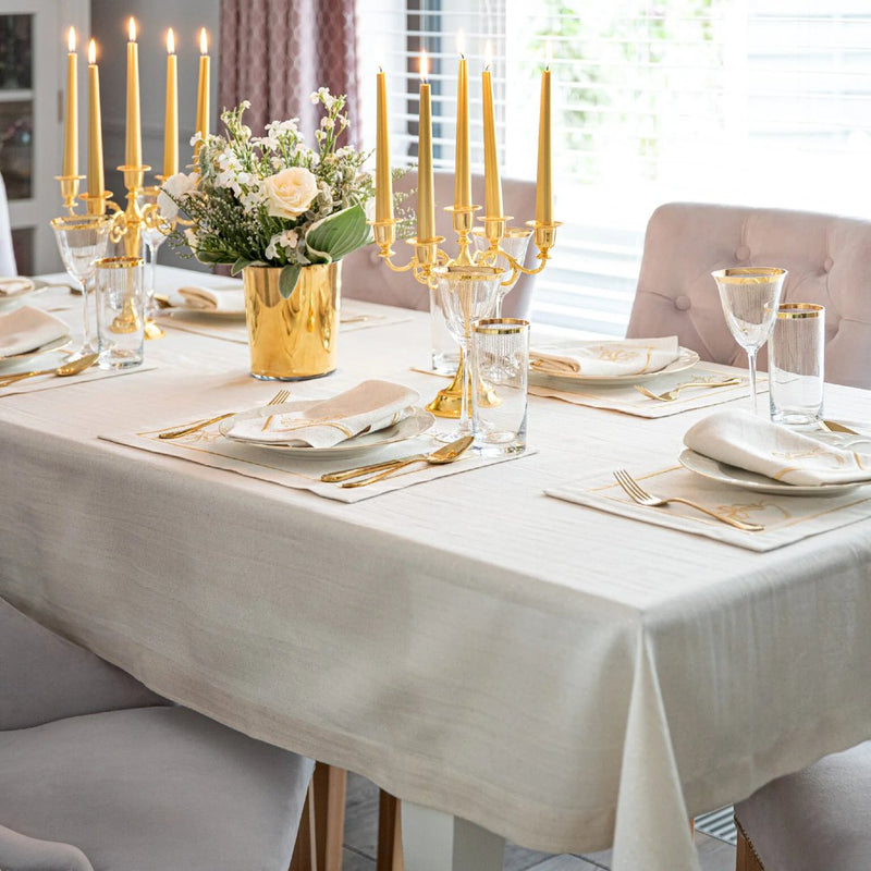 Embroidered candy cane motif detail on gold holiday placemat on luxe Christmas table setting.
