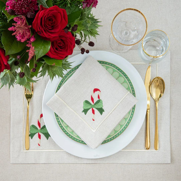 Beige cotton placemat with embroidered candy cane and gold border styled on festive tablescape.