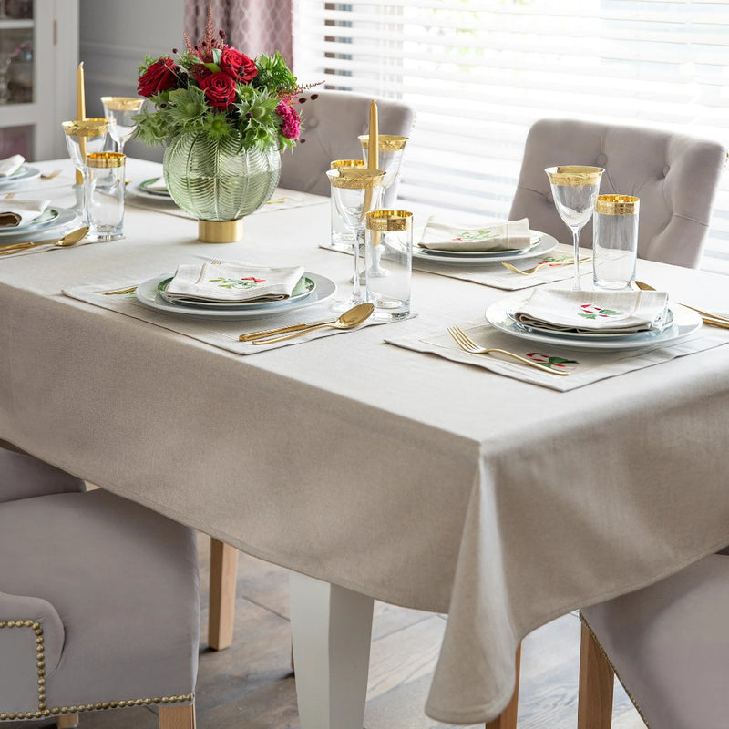 Beige cotton placemat with embroidered candy cane and gold border styled Christmas table setting.