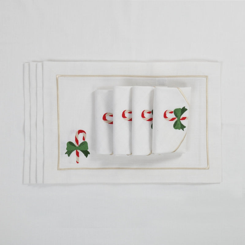 White cotton placemat with embroidered candy cane and gold border with matching napkins.