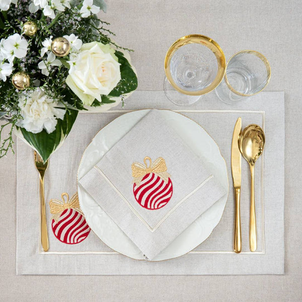 Beige cotton placemat with embroidered Christmas bauble and gold border on Christmas table setting.