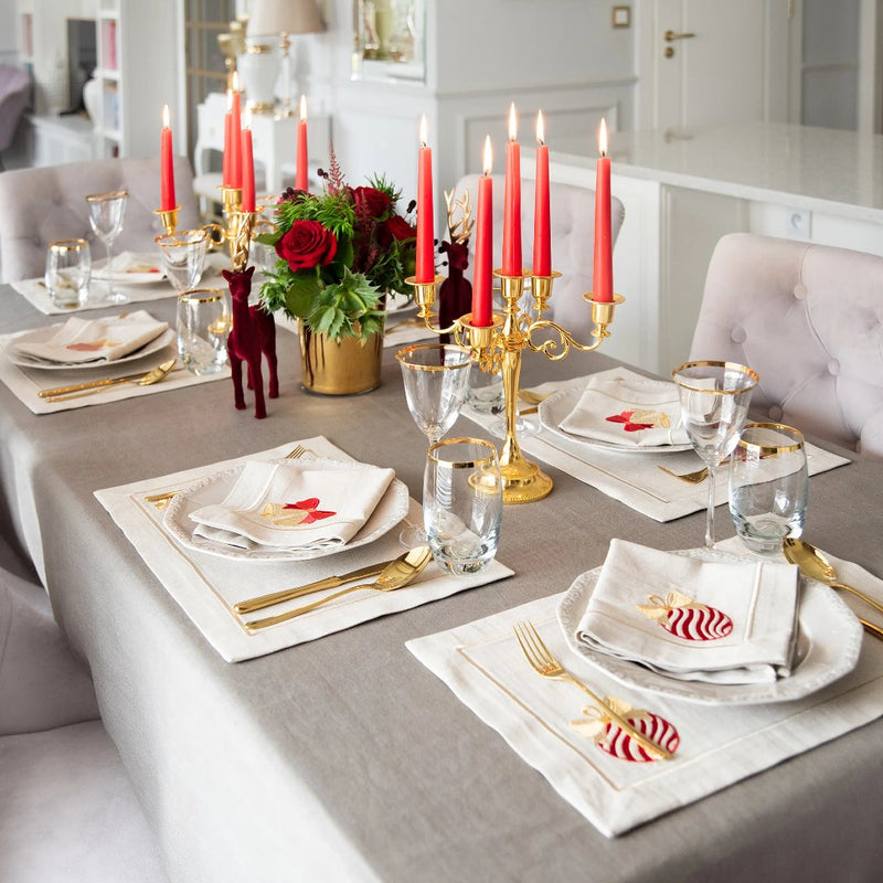 Beige cotton placemat with embroidered Christmas bauble and gold border styled on festive tablescape.