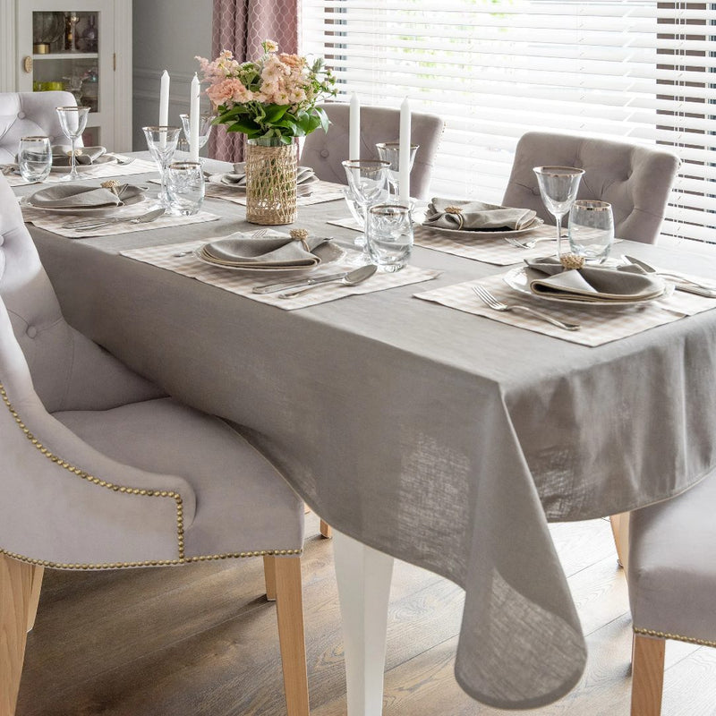 Rectangular beige gingham placemat on grey tablecloth.