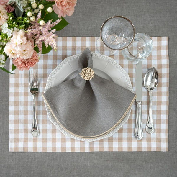 Rectangular beige gingham placemat styled with rattan napkin ring.
