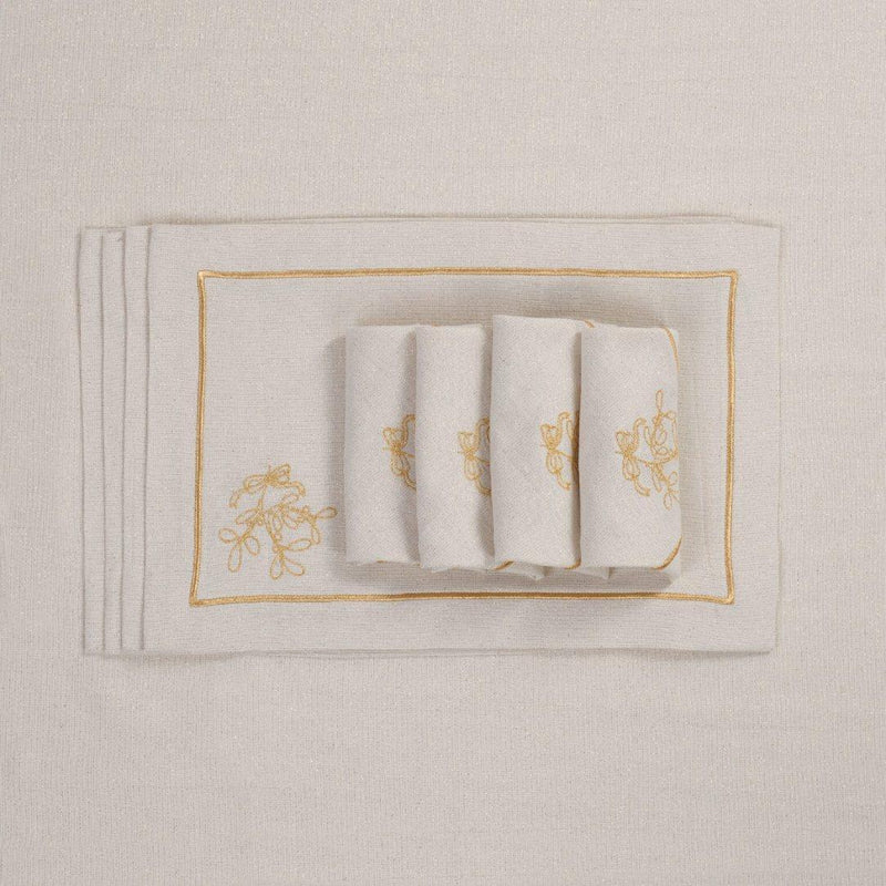 Embroidered mistletoe motif detail on gold holiday placemat with matching napkins.
